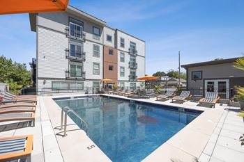 A swimming pool with lounge chairs and a building in the background